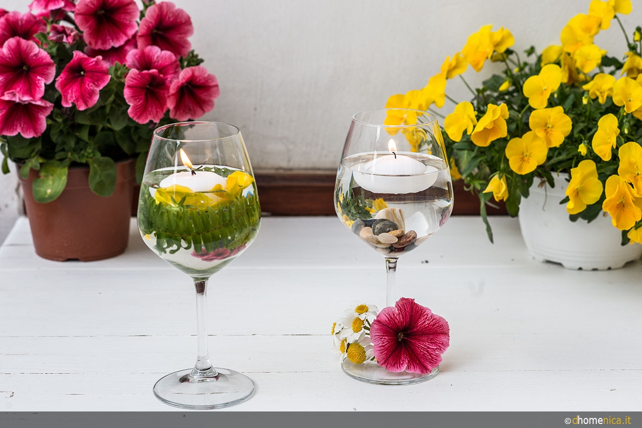 Bicchiere di vino pieno di boccioli di fiori di rosa essiccati che si  trovano sul tavolo blu.