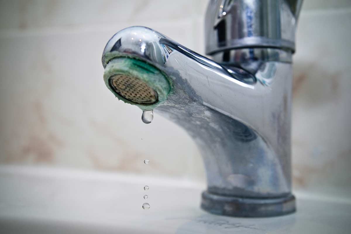 Rubinetto da bagno con incrostazioni di calcare ben visibili sull’aeratore; esempio tipico di superficie che necessita la pulizia con acido citrico, foto di © Florian Villesèche - stock adobe